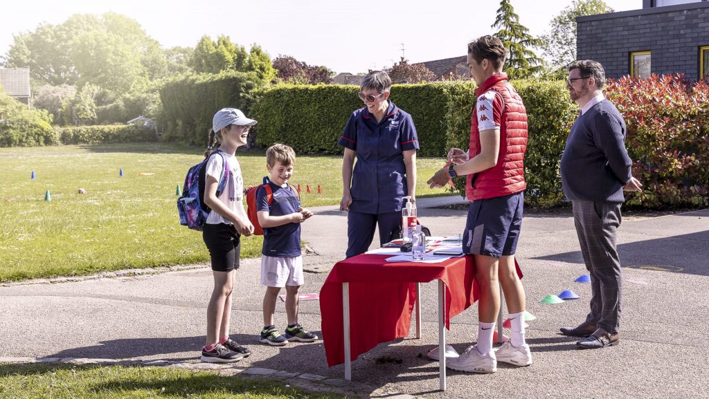 Parent taking children to the school, Head and sports coach welcome them.