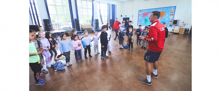 Row of primary school aged children warming up for a active sports sessions delivered by childcare specialists, LSC