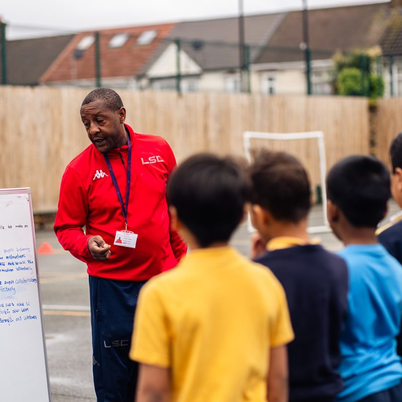 LSC PE Specialist delivering PE Lesson outside in Primary School Playground to a group of Year 3 pupils